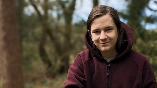 An image of Archie Williams standing in front of some trees and other greenery